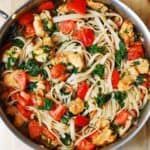 a pan filled with pasta and vegetables on top of a wooden table