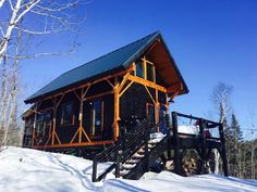 a log cabin sits on top of a snow covered hill with stairs leading up to it