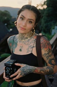 a woman with tattoos holding a camera