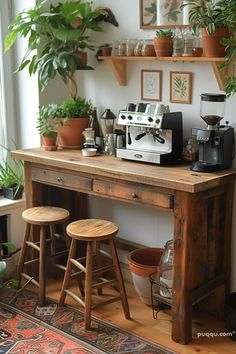 a wooden table topped with two stools next to a coffee maker and potted plants