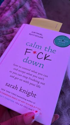 a person holding a book in their hand with the title calm the fock down on it