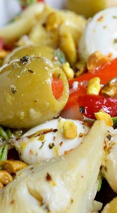 an assortment of food including olives, peppers, and other vegetables on a plate