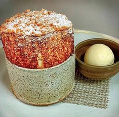 a cake sitting on top of a white plate next to a bowl filled with ice cream