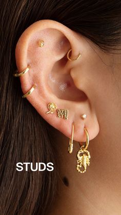 a woman wearing gold ear piercings with the word stud on it