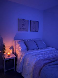 a bed with two pictures on the wall above it and a night light next to it