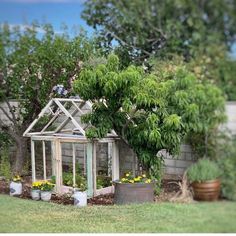 an old greenhouse is surrounded by potted plants