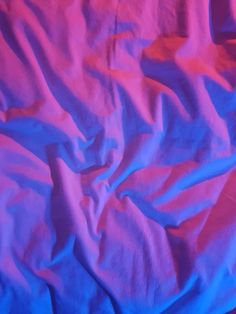 an unmade bed with blue and pink sheets