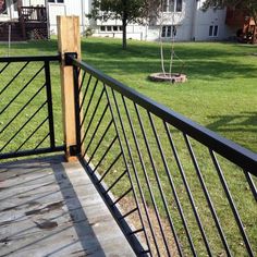 a wooden deck with metal railings in the grass