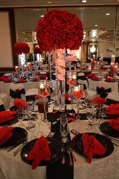 a table set with black and white plates, red napkins, silverware and centerpieces