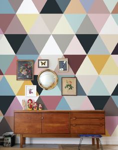 a room with a dresser, mirror and colorful wallpaper on the walls behind it