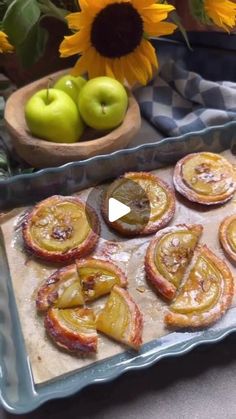 some food is laying out on a tray with sunflowers and apples in the background