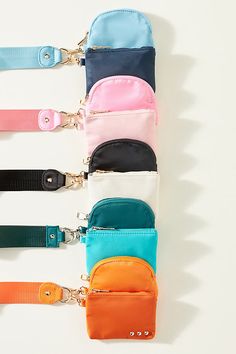 four different colored purses are lined up on a white surface and one has a key chain attached to it