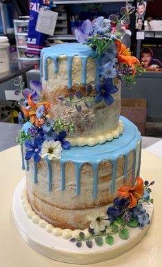 a three tiered cake with blue icing and flowers