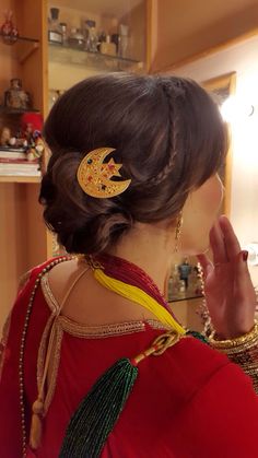 a woman in a red dress with a gold brooch on her left shoulder and an elaborate hair piece on her right hand