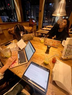 two women sitting at a table with laptops