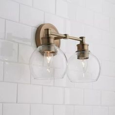 two clear glass globe lights on a white tiled wall