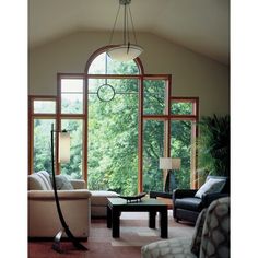 a living room filled with furniture and lots of large windows overlooking the trees in the distance