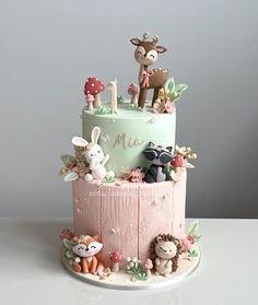 a three tiered cake with animals and flowers on the top is decorated in pastel colors