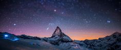 the night sky is filled with stars and bright lights as it shines brightly over snow covered mountains