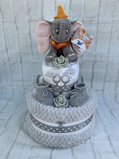 an elephant is sitting on top of a diaper cake that has grey and white trim