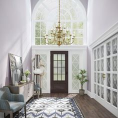 a large room with a chandelier and two chairs in front of the door