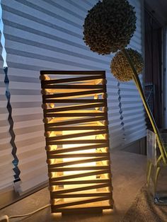 a vase filled with flowers sitting on top of a table next to a window covered in blinds