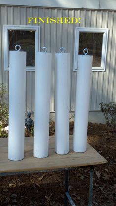 four white cylinders are stacked on top of each other in front of a metal building