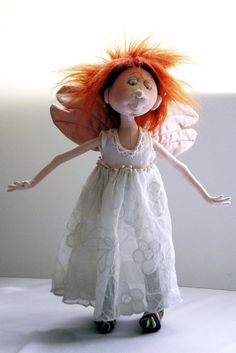 a doll with red hair wearing a white dress