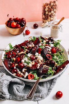 a salad with cherries, feta cheese and nuts in a bowl on a table