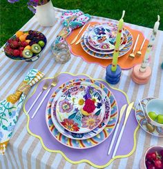 the table is set with colorful plates and fruit