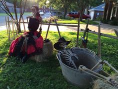 two skeletons are sitting in the grass next to a bucket full of hay and straw bales