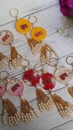 six keychains with tassels and beads on top of a wooden table