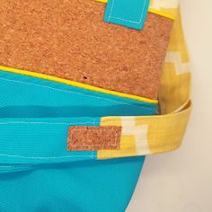 a close up of a blue and yellow handbag with cork in the front pocket