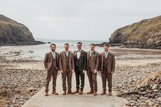 a group of men standing next to each other on top of a rocky beach near the ocean