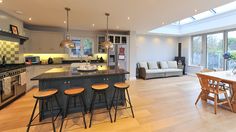 a large open kitchen and living room area with an island in front of the dining table