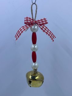 a bell ornament hanging from a red and white ribbon