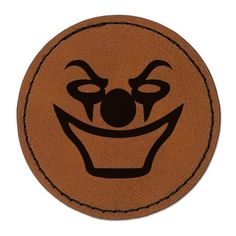 a close up of a face on a brown leather circle with an evil clown's smile