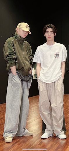 two young men standing next to each other on a wooden floor