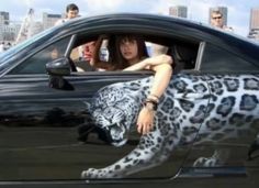 a woman sitting in the drivers seat of a black car with a white tiger painted on it