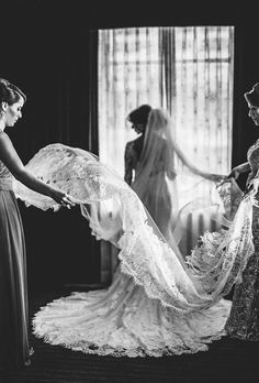 two women in dresses and veils are looking at another woman's wedding dress