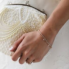 a woman's hand holding a white purse with pearls on the outside and inside