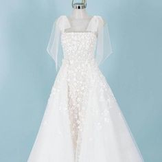 a white wedding dress on display against a blue background