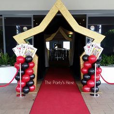 an entrance to a casino themed party with red carpet and black and white balloons on it