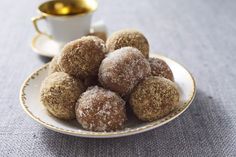 some sugared donuts are on a plate next to a cup