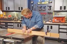 a man working on a piece of wood in his garage with tools and workbench behind him