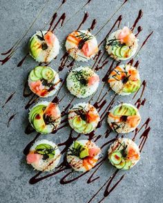 sushi with sauce drizzled over it on a gray surface, including cucumbers and avocado