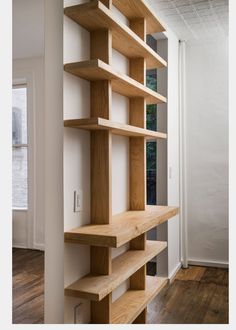 an empty book shelf in the corner of a room with wood floors and white walls