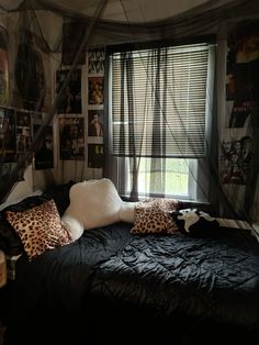 a bed with black sheets and pillows in a room that has pictures on the walls