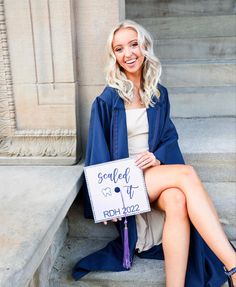 a woman sitting on the steps with her graduation cap and gown in front of her