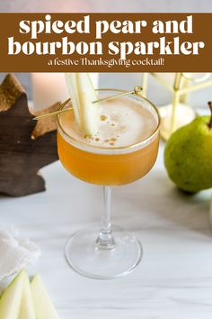 a glass filled with an orange and white drink on top of a table next to pears